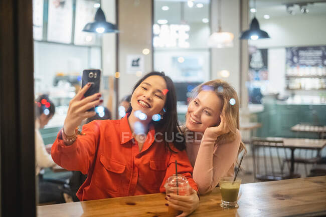 Les jeunes femmes prennent selfie dans un café — Photo de stock