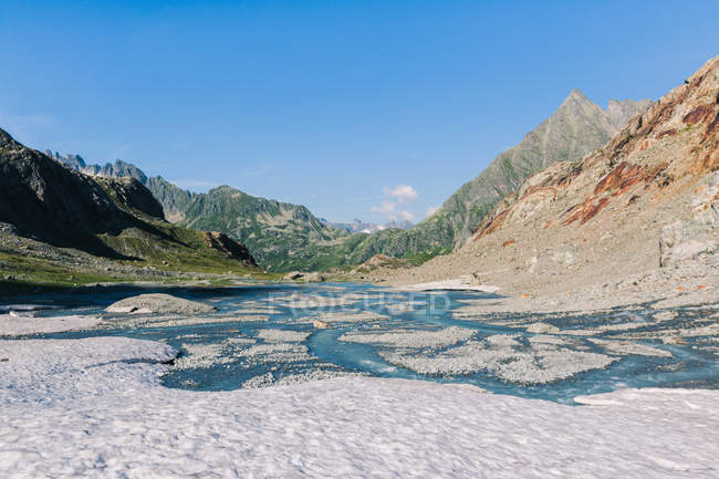 Удивительный пейзаж реки, протекающей среди камней между горами Швейцарии — стоковое фото