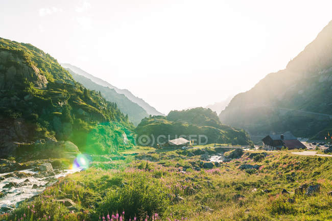 Amazing landscape of houses by river flowing among stones between mountains in Switzerland — Stock Photo