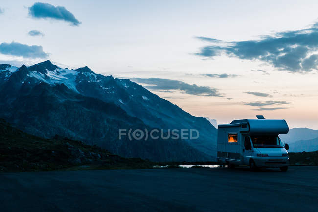 Wohnmobil fährt in der Dämmerung in der Schweiz am See mit kristallklarem Wasser entlang — Stockfoto