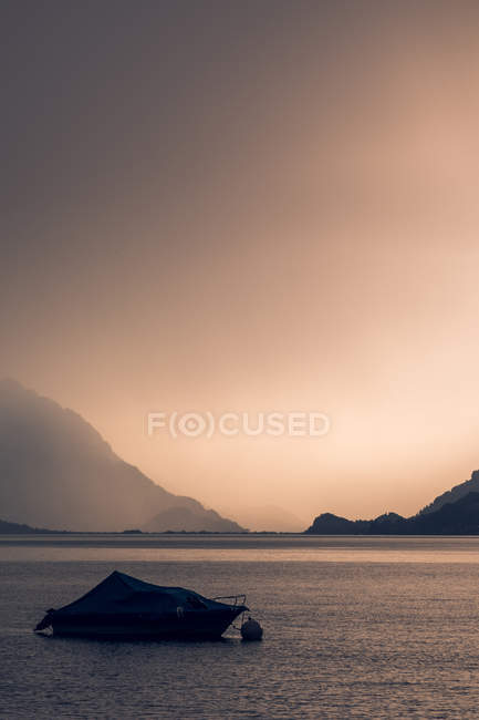 Paesaggio tranquillo di barca scura in acqua ondulata sotto cielo grigio nuvoloso in montagne in Svizzera — Foto stock
