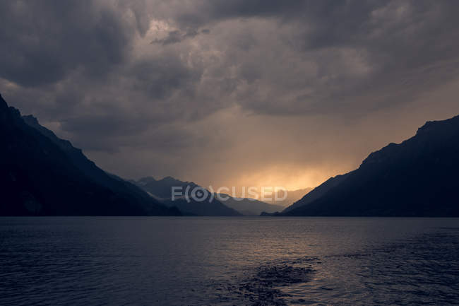 Ruhige Landschaft aus dunkel plätscherndem Wasser unter grauem bewölkten Himmel in den Bergen der Schweiz — Stockfoto