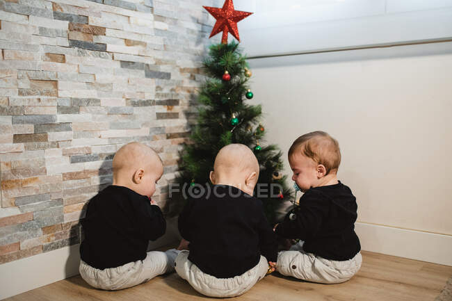 Bebês anônimos perto da árvore de Natal — Fotografia de Stock