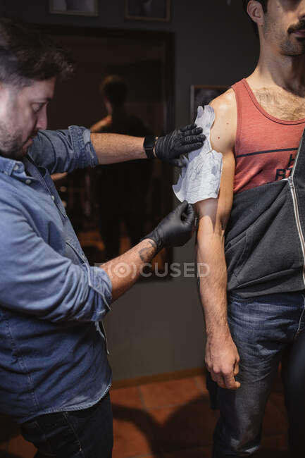 Tätowiermeister befestigt Schablone am Unterarm des Kunden — Stockfoto