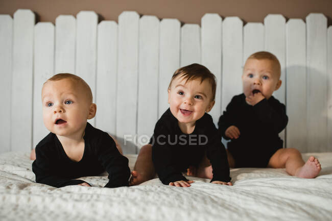 Bebés felices sentados en la cama - foto de stock