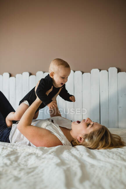 Madre jugando con el bebé en la cama - foto de stock
