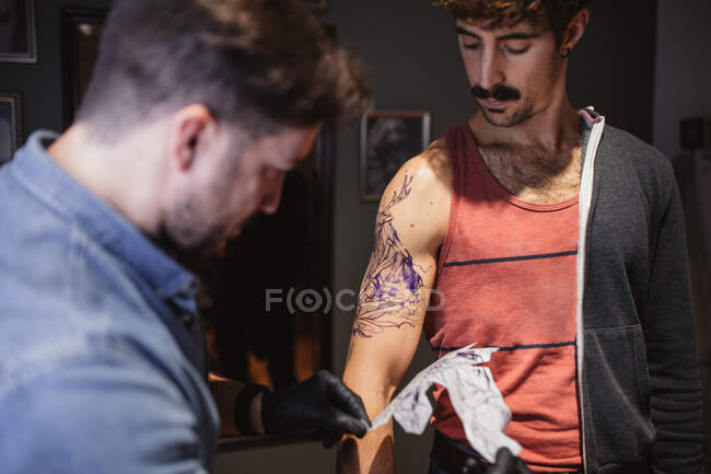 Tattoo master removing template on client's forearm — Stock Photo