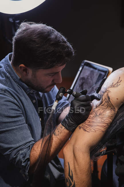 Mestre fazendo tatuagem no antebraço do cliente masculino — Fotografia de Stock