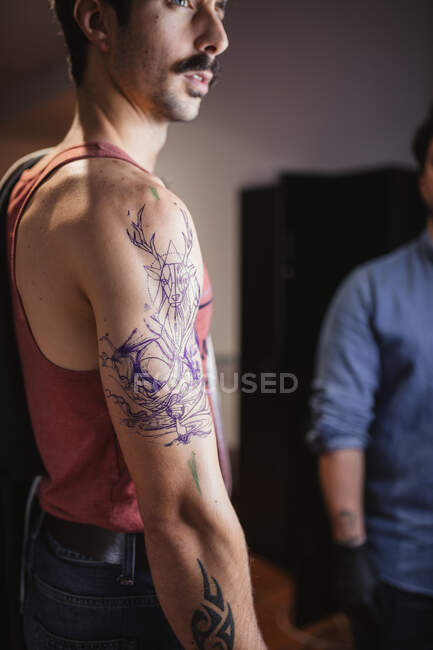 Homme regardant le croquis de tatouage sur le bras dans le salon — Photo de stock