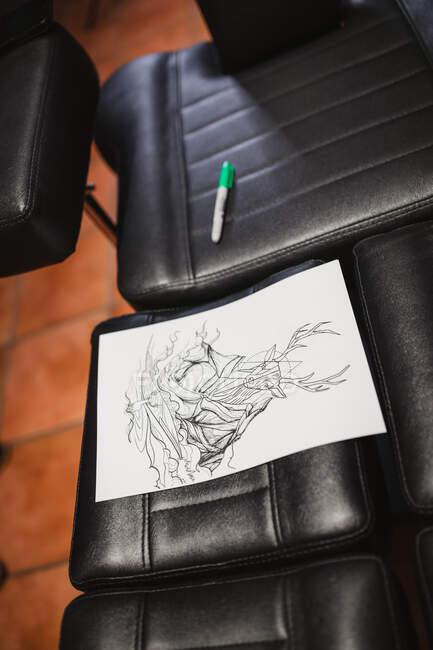 Croquis de tatouage sur chaise en cuir dans le salon — Photo de stock