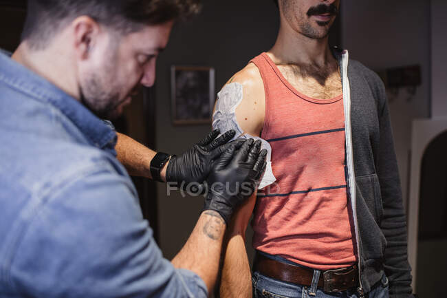 Tattoo master attaching stencil on forearm of client — Stock Photo