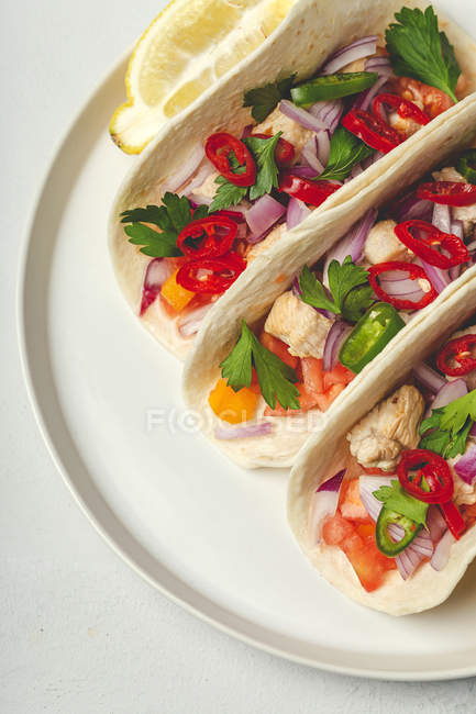 Мексиканские тако со свежими овощами и курицей на белом фоне — стоковое фото