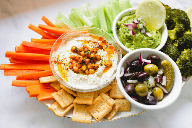 Tasty hummus and sauces decorated with bright cut vegetables on table — Stock Photo