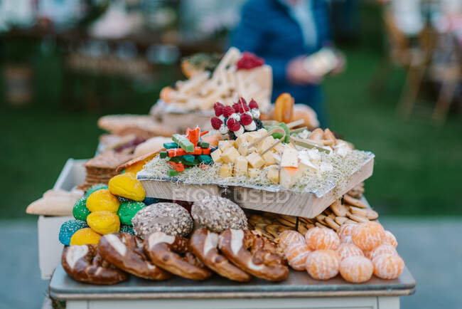 Wooden tray with canapes placed on tray with cookies and fruits in candy bar served during wedding ceremony outdoors — Stock Photo