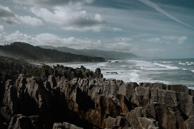 Blaue Wellen spülen bei hellem Tag felsige Meeresküste — Stockfoto
