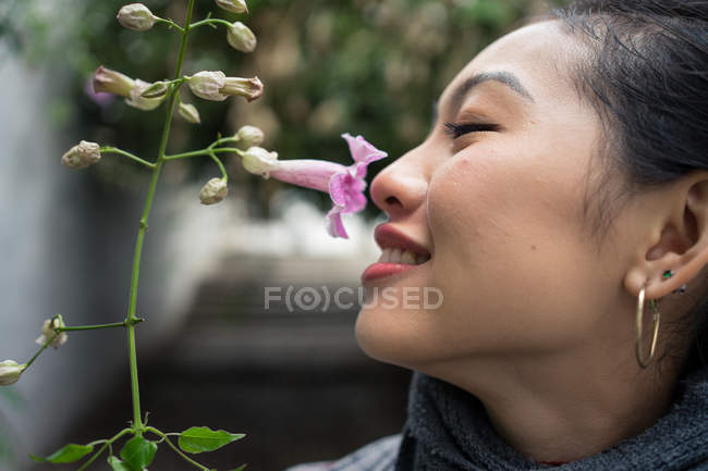 Close-up da mulher asiática sorrindo enquanto desfruta de cheiro de flor roxa — Fotografia de Stock