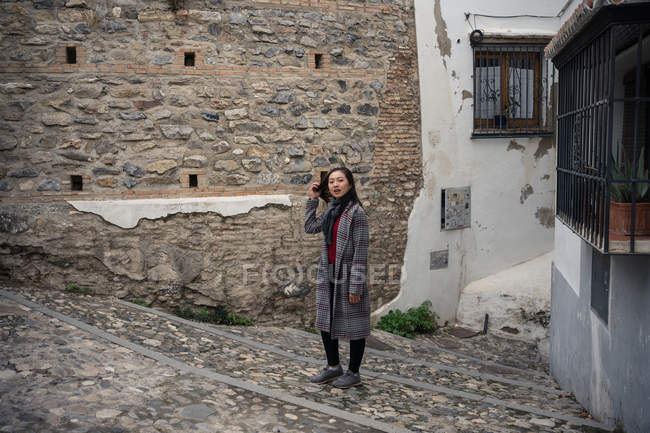Young Asian woman in stylish casual coat standing on old cobblestone stairs of ancient alley — Stock Photo