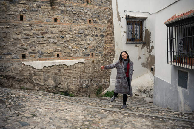 Asian woman walking on aged cobblestone steps in city alley — Stock Photo
