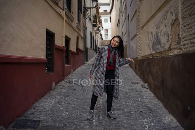 Радостная азиатская туристка на старой раскаленной узкой улочке — стоковое фото
