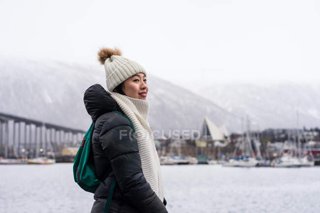 Asian female tourist in warm wear at snowy field near city — Stock Photo