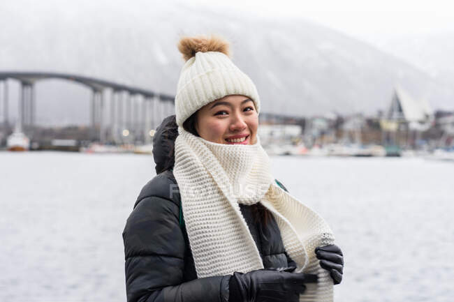 Азиатская туристка в теплой одежде на снежном поле недалеко от города — стоковое фото