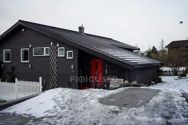 Large black barn against snowy hill and residential houses in countryside — Stock Photo