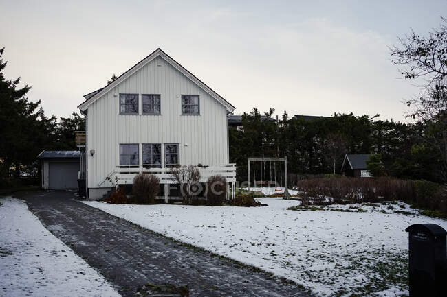 Granero rojo grande contra colina nevada y casas residenciales en el campo - foto de stock