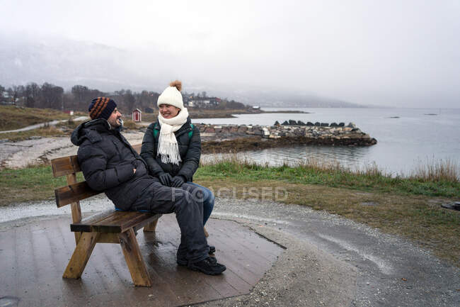 Turistas relajándose en el banco en la elevación por mar - foto de stock
