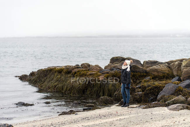 Donna sulla spiaggia rocciosa di riva al mare — Foto stock