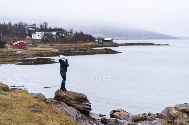 Female standing on stone cliff off coast — Stock Photo
