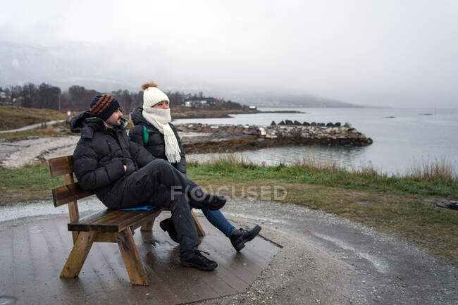 Tourists relaxing on bench on elevation by sea — Stock Photo