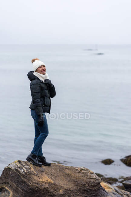 Жінка стоїть на кам'яній скелі біля берега — стокове фото