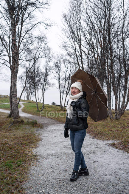 Woman walking in park with umbrella — Stock Photo