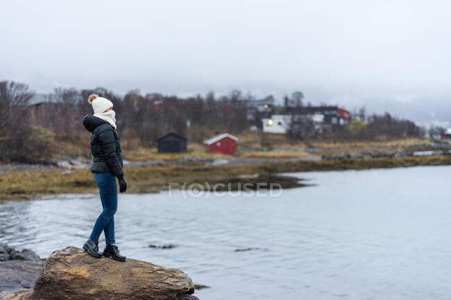 Женщина стоит на каменной скале у берега — стоковое фото