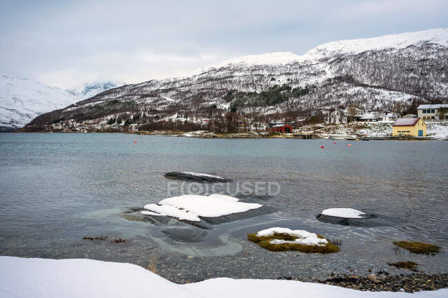 Норвежская природа с морем и заснеженными горами с домиками на побережье — стоковое фото