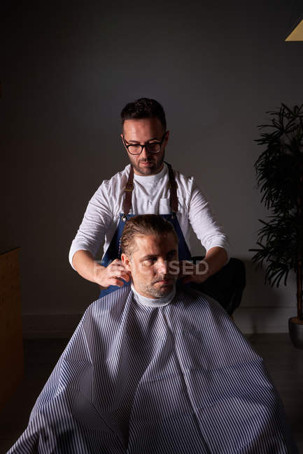 Adult Hairdresser In White Shirt And Blue Apron Focusing And