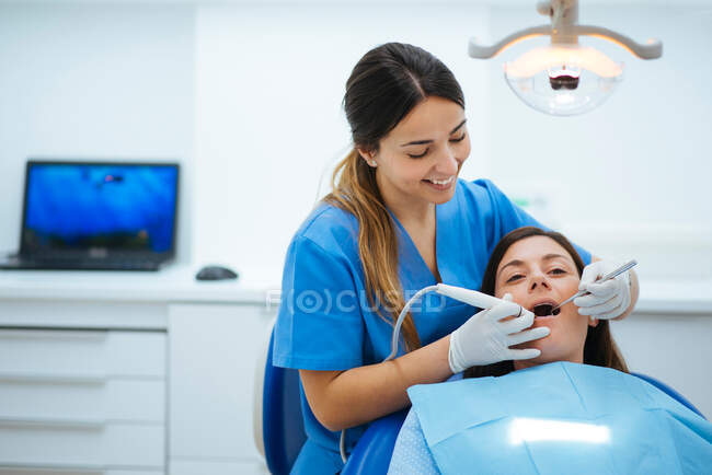 Dentista e assistente examinando boca de paciente em cadeira com t — Fotografia de Stock