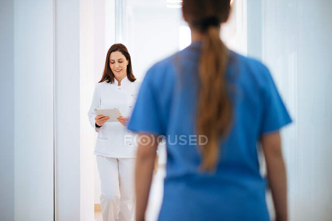 Doctor en uniforme blanco caminando a lo largo del pasillo - foto de stock