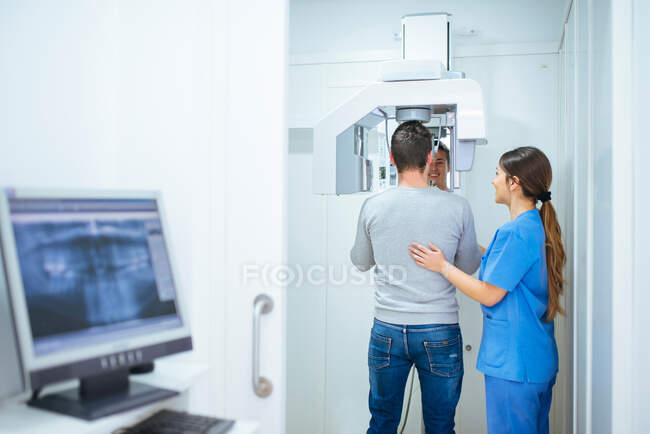 Asistente dental ayudando al cliente a hacer rayos X - foto de stock