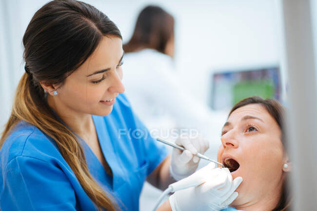 Dentista e assistente esaminando la bocca del paziente in sedia con t — Foto stock