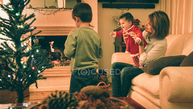 Madre che gioca con il bambino mentre figlio addobba l'albero di Natale — Foto stock