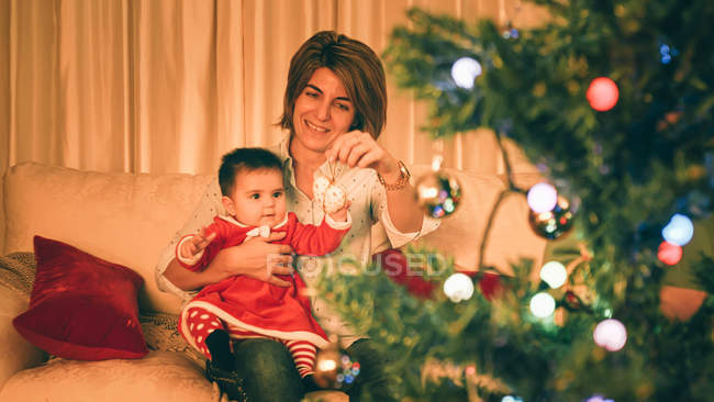 Mother playing with baby near Christmas tree — Stock Photo