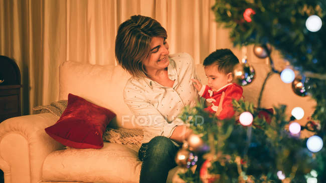 Мама играет с ребенком рядом с елкой — стоковое фото