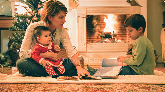 Мать читает книгу с сыном накануне Рождества — стоковое фото