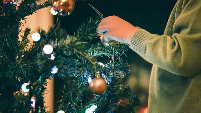 Cropped image of Boy decorating Christmas tree in evening — Stock Photo