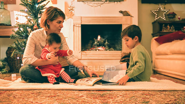 Мать читает книгу с сыном накануне Рождества — стоковое фото