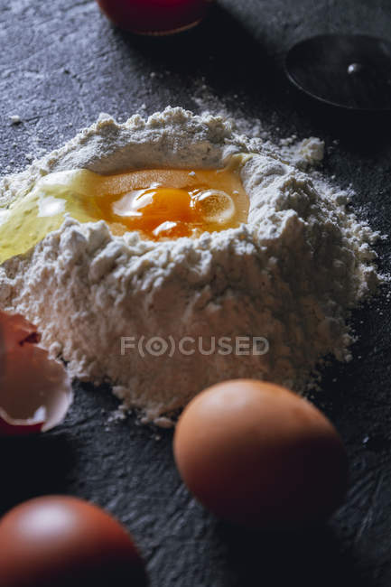 Nahaufnahme von zerbrochenem Ei in Mehl auf strukturierter schwarzer Oberfläche — Stockfoto