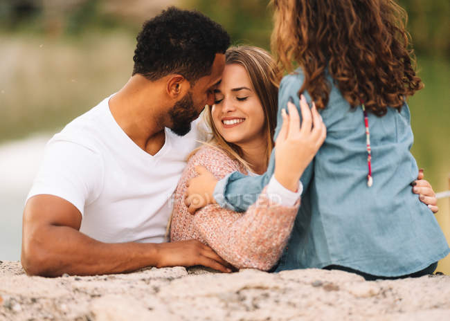 Pais multirraciais casuais felizes em conjunto com a filha na natureza — Fotografia de Stock