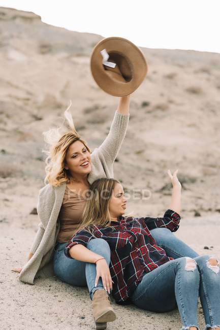 Two beautiful blonde women cuddling as resting in desert at daytime — Stock Photo