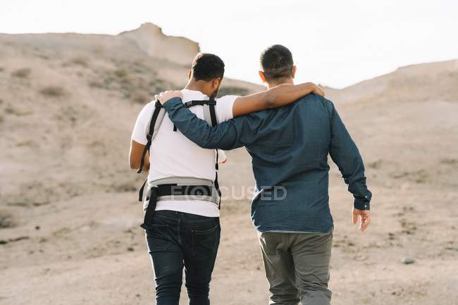 Back view of casual men with baby carrier strolling on nature at daytime — Stock Photo